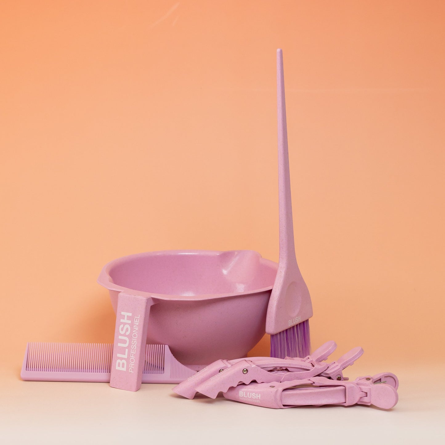 Pink BLUSH hair treatment application kit with mixing bowl, brush, tail comb, and three clips for precise and mess-free application