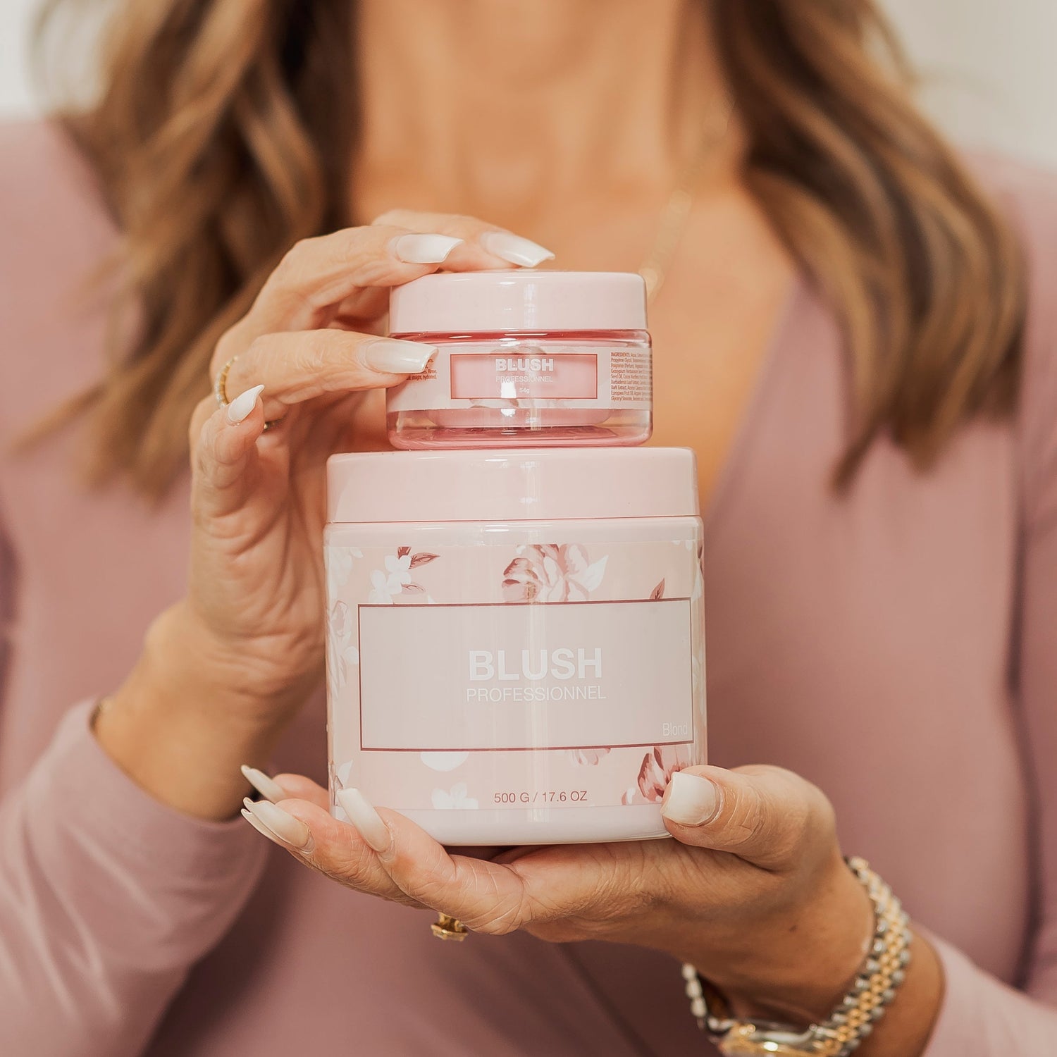 Close-up of BLUSH Cure Absolue Blond hair treatment in 500 g and 54 g sizes held in hands, showcasing the professional hair repair formula designed to smooth, nourish, and strengthen blonde hair