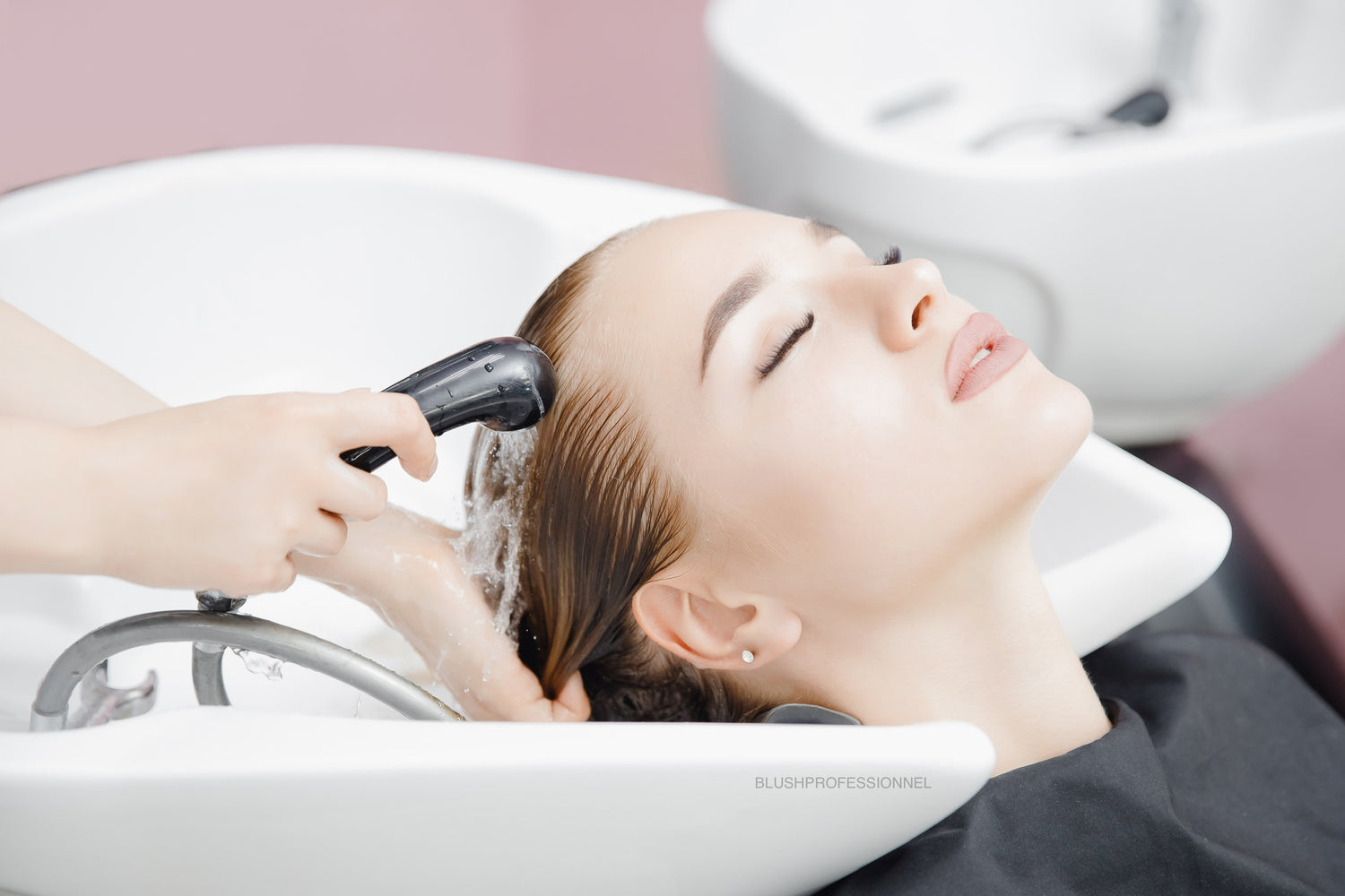 Lifestyle image of a client having her hair washed in a salon basin, representing a gentle cleansing and professional hair care experience