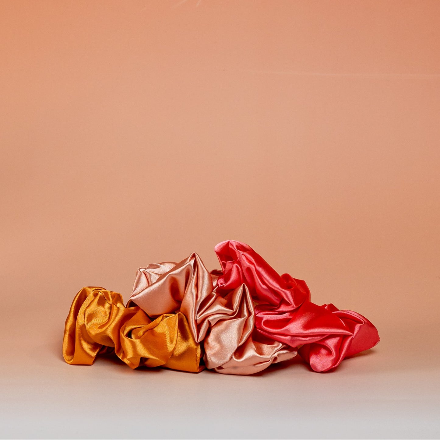 Set of 3 orange BLUSH satin scrunchies designed to protect hair and reduce breakage