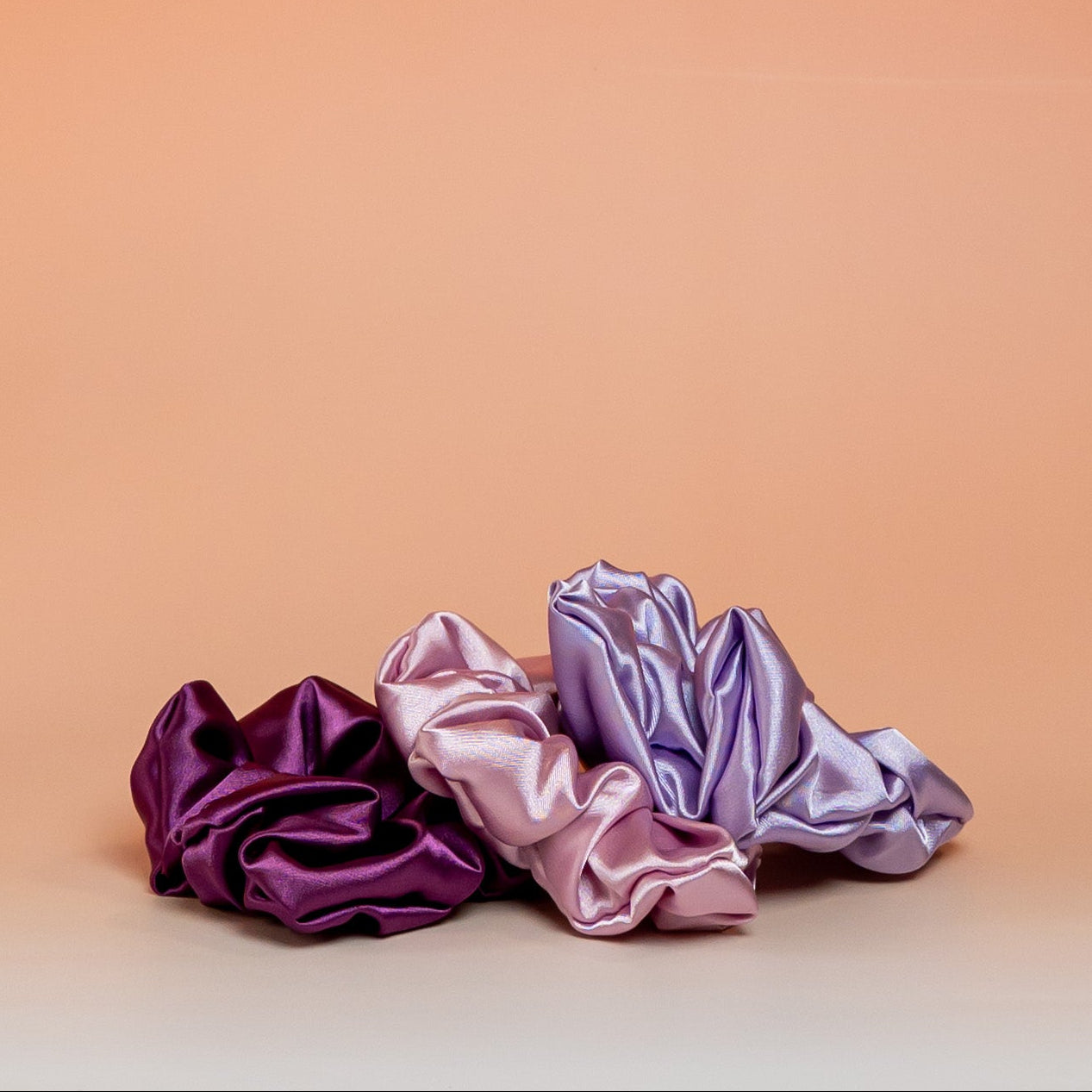 Set of 3 purple BLUSH satin scrunchies that gently hold hair while reducing friction and breakage