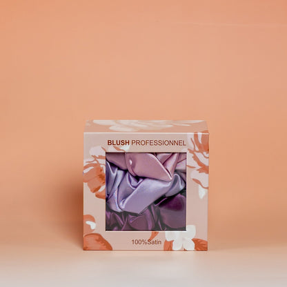 Purple BLUSH box containing a set of 3 satin scrunchies designed to help reduce friction and support healthy-looking hair.